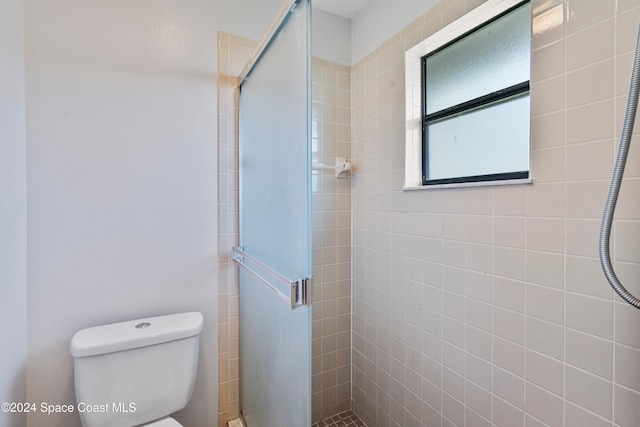 bathroom with a shower with shower door and toilet