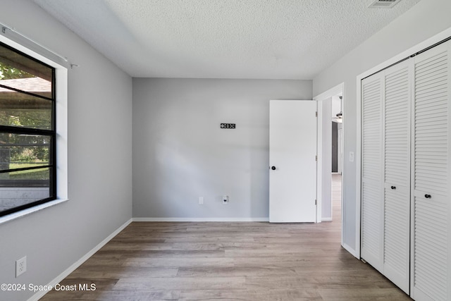 unfurnished bedroom featuring a closet, light hardwood / wood-style floors, and a textured ceiling