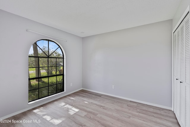 unfurnished room featuring light hardwood / wood-style flooring and a textured ceiling