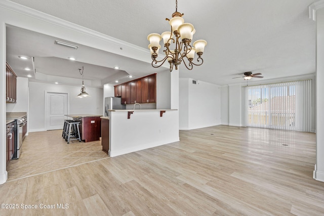 4975 Dixie Hwy NE Unit 201, Palm Bay, FL 32905 - kitchen featuring stainless steel fridge, open floor plan, light wood-style flooring, ceiling fan, and a kitchen bar