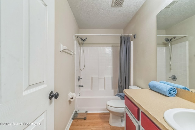 full bathroom with shower / bath combo, toilet, wood-type flooring, vanity, and a textured ceiling