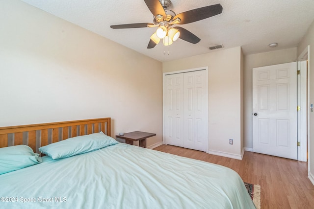 bedroom featuring light hardwood / wood-style flooring, a textured ceiling, a closet, and ceiling fan