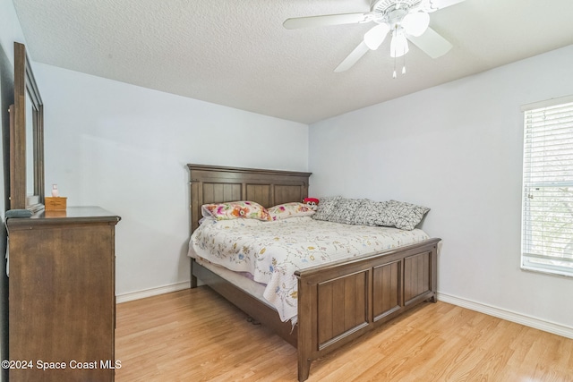 bedroom with a textured ceiling, light hardwood / wood-style floors, and ceiling fan