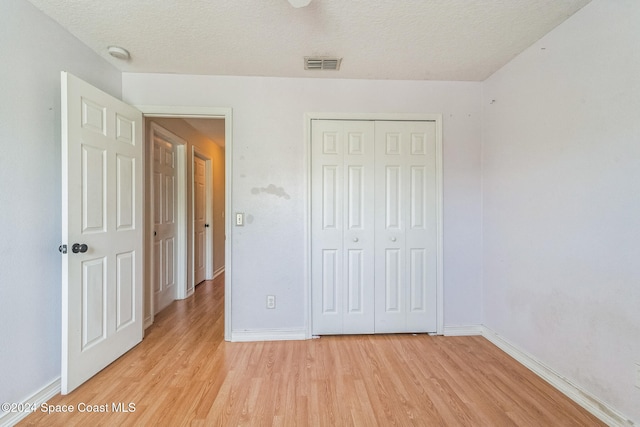 unfurnished bedroom with a closet, a textured ceiling, and light hardwood / wood-style floors