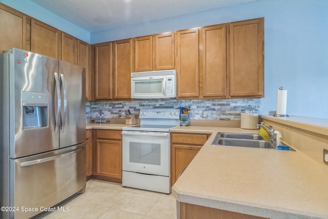 kitchen featuring white appliances, light tile patterned flooring, sink, backsplash, and a textured ceiling