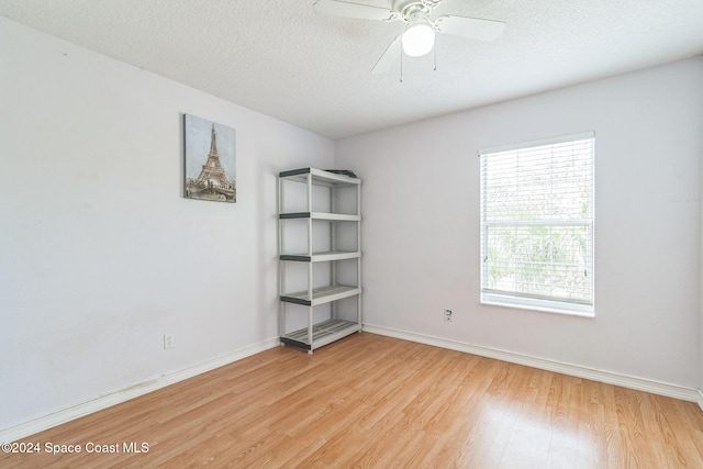 empty room featuring light hardwood / wood-style flooring, a textured ceiling, and ceiling fan