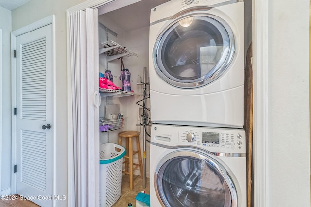 laundry room with tile patterned flooring and stacked washing maching and dryer