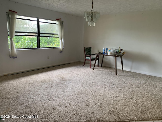 interior space with an inviting chandelier, a textured ceiling, and carpet flooring