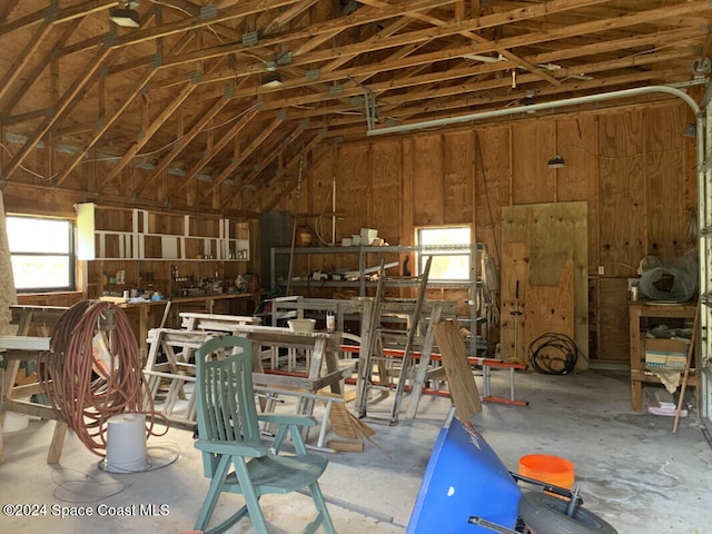 miscellaneous room featuring concrete flooring, a workshop area, and vaulted ceiling