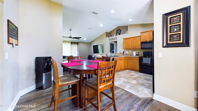 dining room with dark hardwood / wood-style floors, ceiling fan, sink, and vaulted ceiling