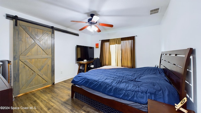 bedroom featuring dark wood-type flooring, a barn door, and ceiling fan