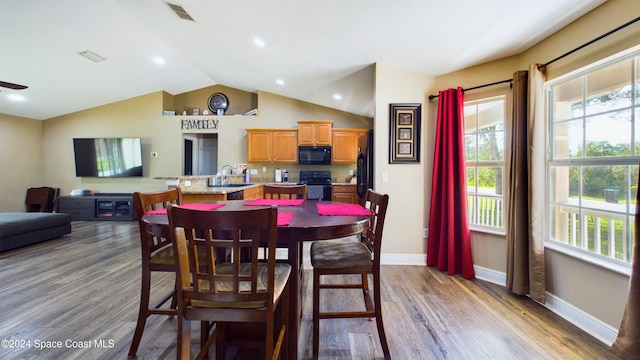 dining room with ceiling fan, sink, dark wood-type flooring, and vaulted ceiling