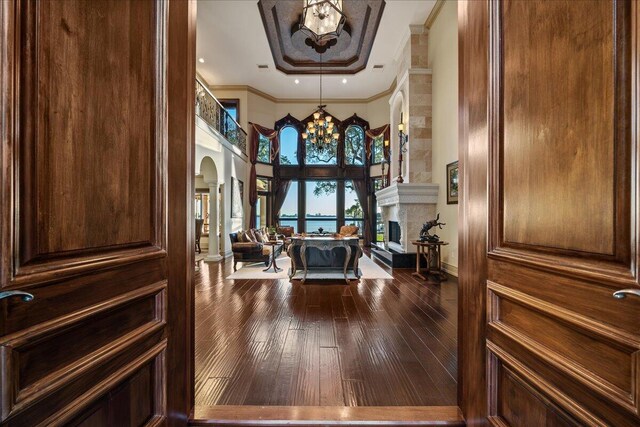 808 N Riverside Dr, Indialantic, FL 32903 - foyer entrance featuring arched walkways, a chandelier, dark wood-style flooring, a high ceiling, and a fireplace