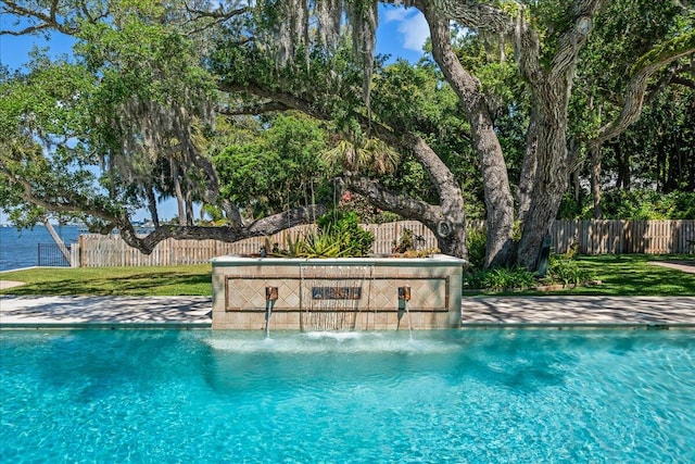 view of swimming pool with a water view, pool water feature, and a lawn