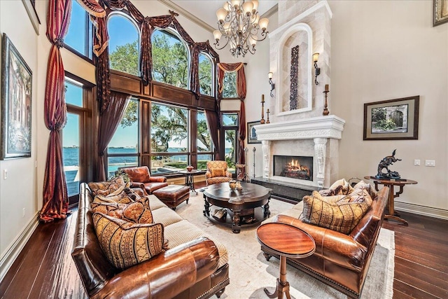 living room with a water view, a notable chandelier, hardwood / wood-style flooring, and a high ceiling