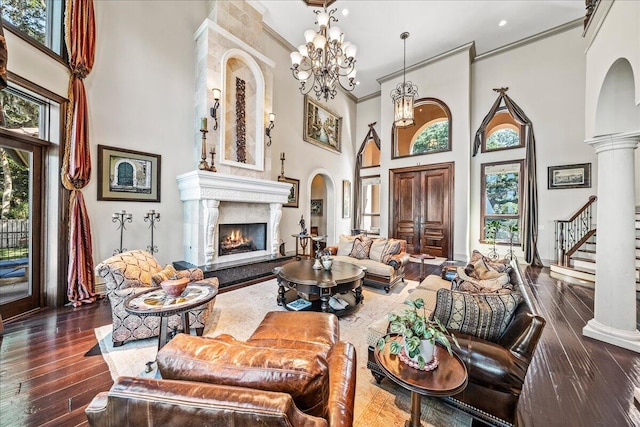 living room with dark wood-type flooring, a healthy amount of sunlight, ornamental molding, and a high ceiling