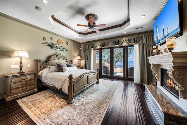 bedroom featuring ceiling fan, access to outside, a tray ceiling, dark hardwood / wood-style floors, and crown molding