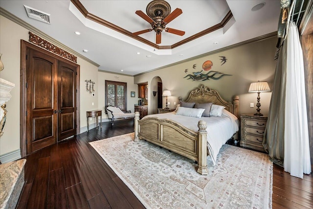 bedroom with ornamental molding, dark hardwood / wood-style floors, a raised ceiling, and ceiling fan