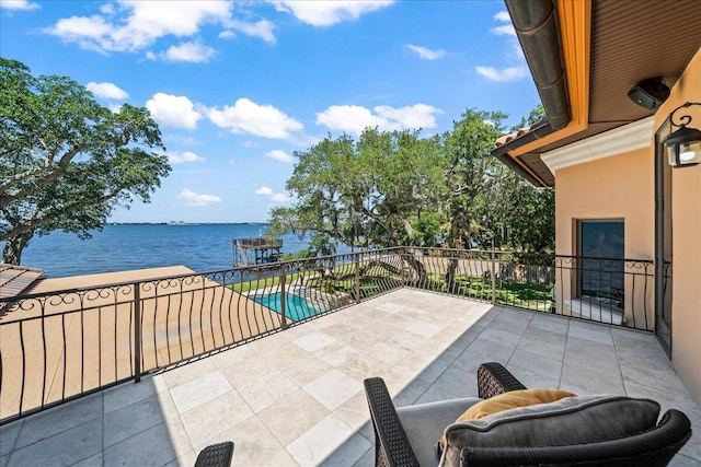 view of patio / terrace featuring a balcony, a water view, and a fenced in pool