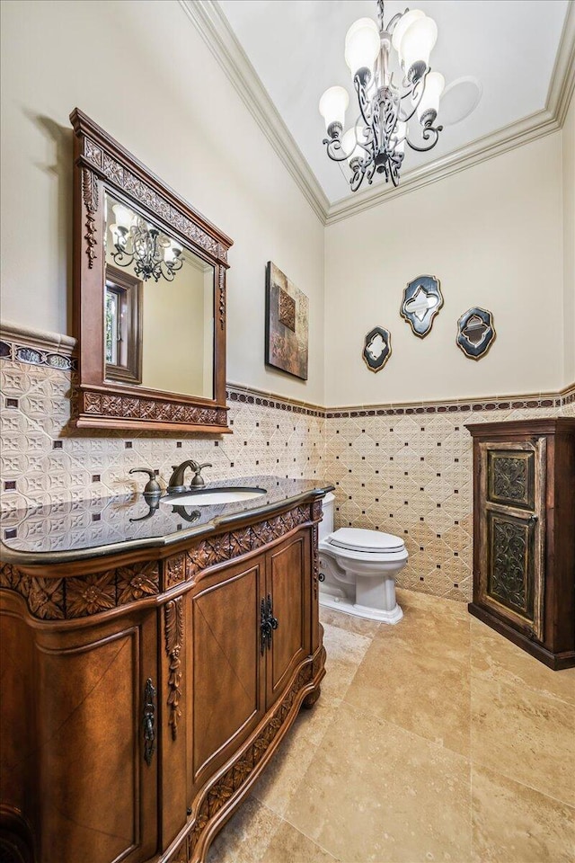 bathroom featuring a chandelier, tile walls, toilet, ornamental molding, and vanity