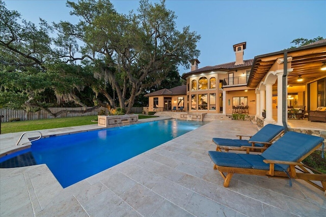 pool at dusk with a patio, a hot tub, and pool water feature