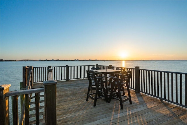 deck at dusk featuring a water view