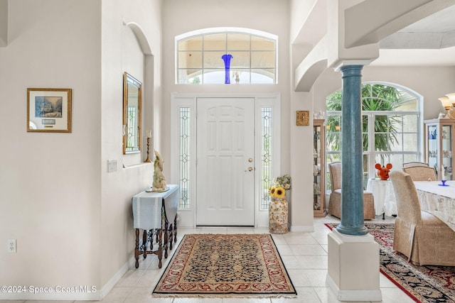 entryway with ornate columns, a towering ceiling, and light tile patterned floors