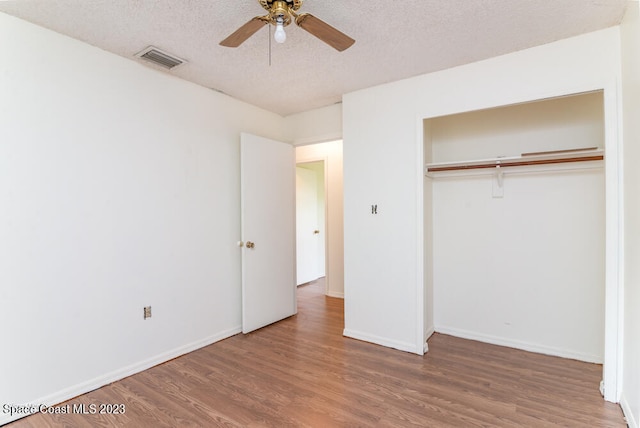 unfurnished bedroom with ceiling fan, a closet, wood-type flooring, and a textured ceiling