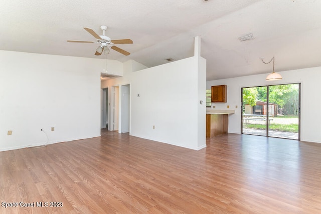 unfurnished living room featuring a textured ceiling, ceiling fan, light hardwood / wood-style flooring, and vaulted ceiling