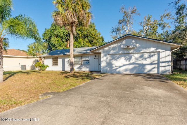 ranch-style home featuring a front lawn, central AC unit, and a garage