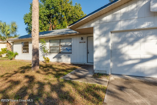 doorway to property with a yard and a garage