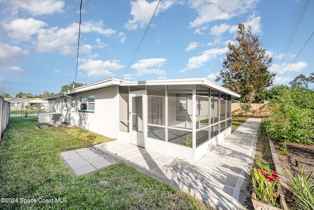 rear view of property featuring a lawn, central AC unit, and a sunroom