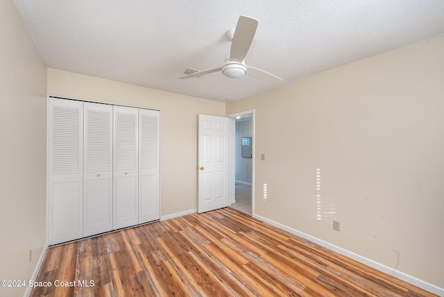 unfurnished bedroom featuring hardwood / wood-style floors, a closet, ceiling fan, and a textured ceiling