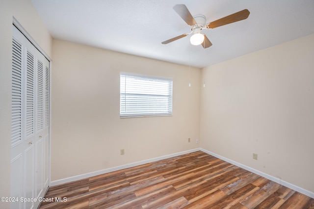 unfurnished bedroom with dark hardwood / wood-style flooring, ceiling fan, and a closet