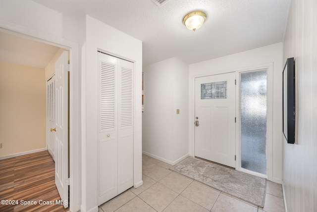 foyer entrance with light tile patterned flooring and a textured ceiling