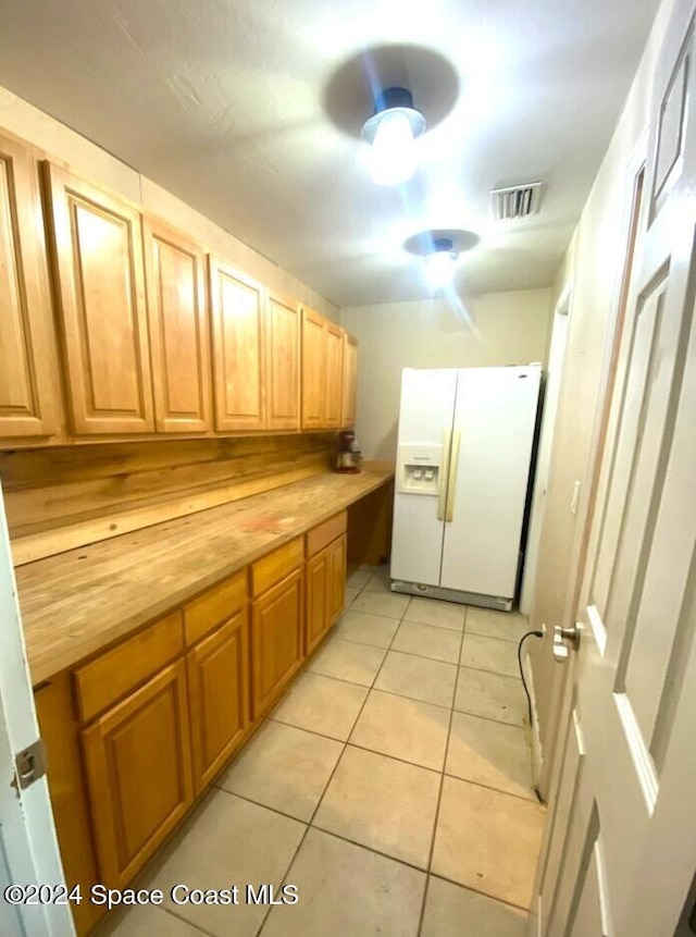 kitchen featuring wood counters, ceiling fan, white fridge with ice dispenser, and light tile patterned floors