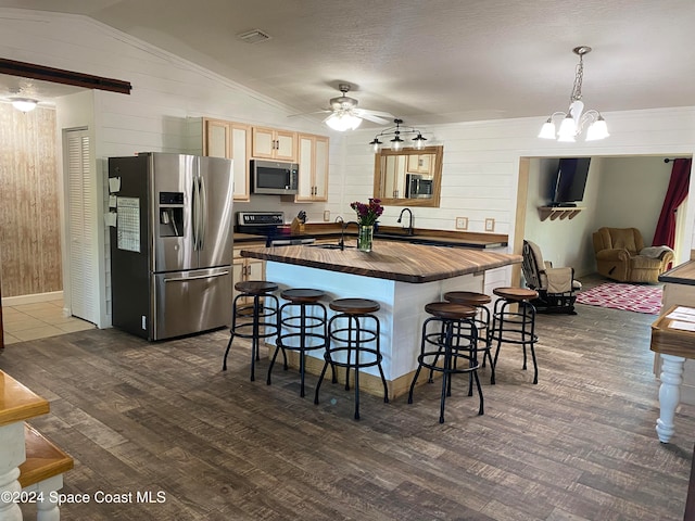 kitchen featuring appliances with stainless steel finishes, decorative light fixtures, a breakfast bar area, dark hardwood / wood-style floors, and lofted ceiling