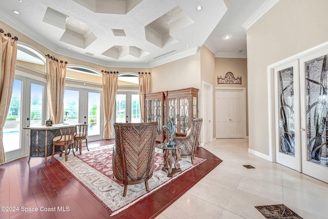 interior space featuring crown molding, a towering ceiling, light hardwood / wood-style floors, french doors, and coffered ceiling