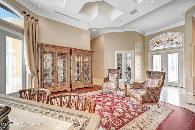 living area featuring french doors, wood-type flooring, ornamental molding, and a high ceiling