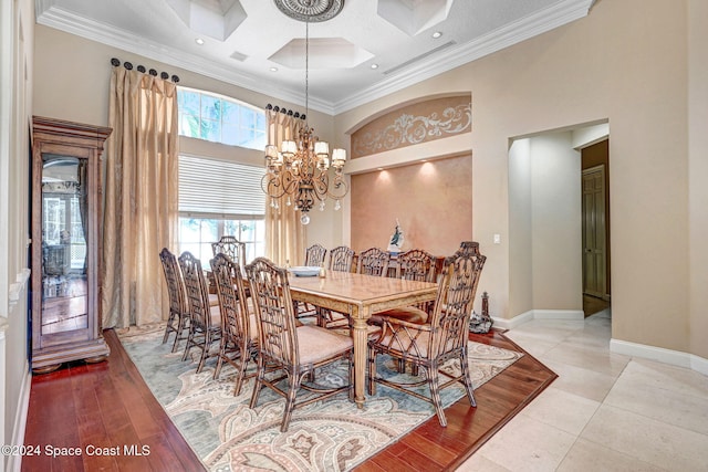 dining area with light hardwood / wood-style floors, crown molding, an inviting chandelier, and a high ceiling