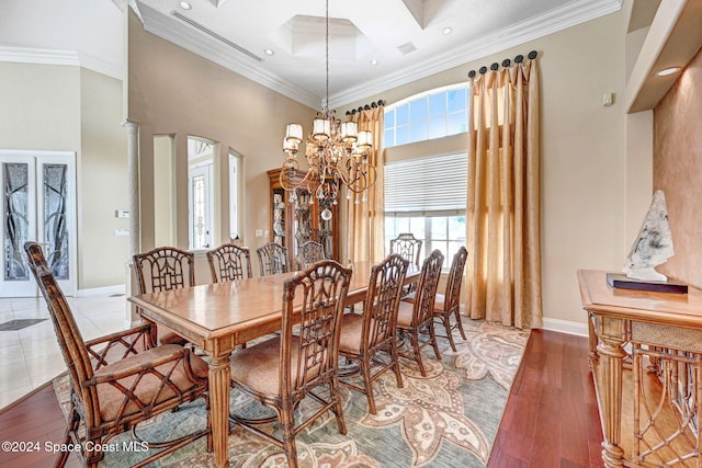dining area featuring ornamental molding, a high ceiling, a chandelier, and hardwood / wood-style flooring
