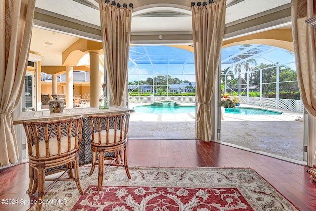 dining area featuring a sunroom, bar area, and hardwood / wood-style floors