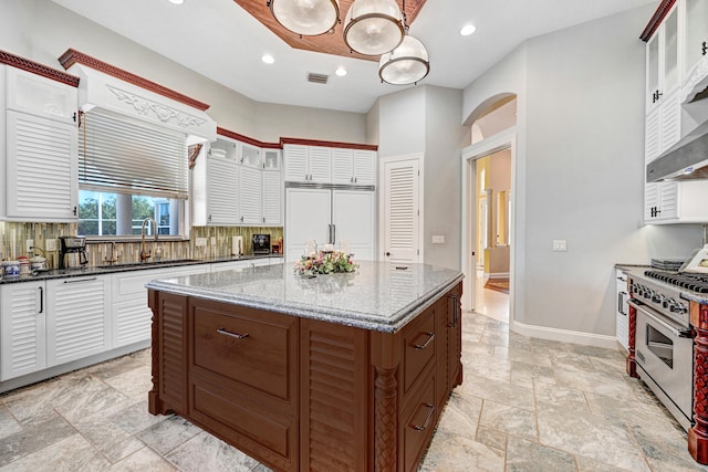 kitchen featuring decorative backsplash, white cabinets, a kitchen island, high quality appliances, and decorative light fixtures