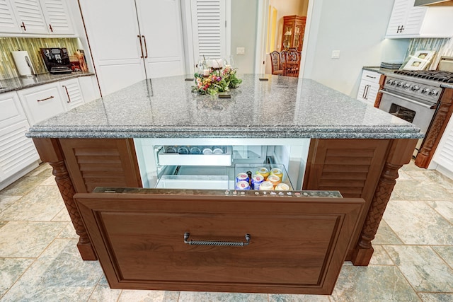 kitchen with white cabinetry, dark stone counters, a kitchen island, and high end stove