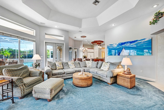 carpeted living room featuring a notable chandelier, french doors, and a tray ceiling