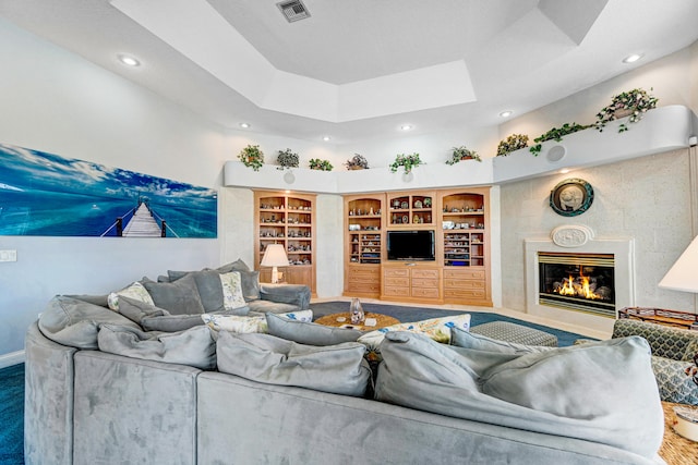 living room featuring built in features and a raised ceiling