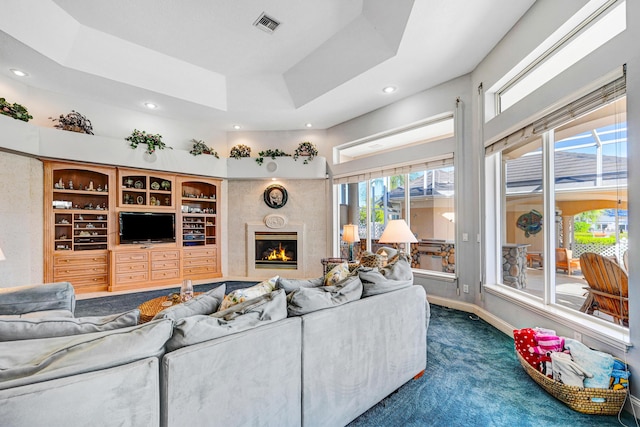 living area featuring visible vents, dark colored carpet, recessed lighting, a high end fireplace, and a raised ceiling