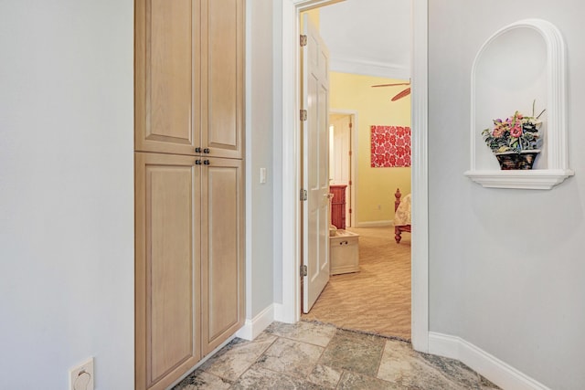 hall with baseboards and stone finish floor