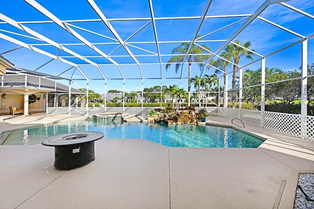 pool with glass enclosure, a fire pit, and a patio area