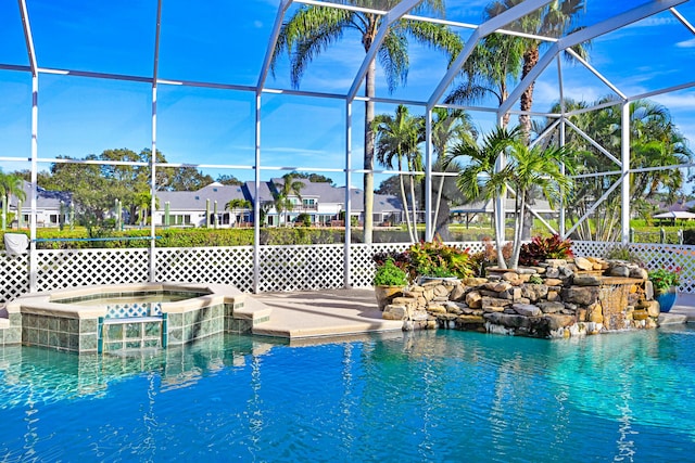 view of pool featuring glass enclosure, a patio area, a pool with connected hot tub, and a residential view